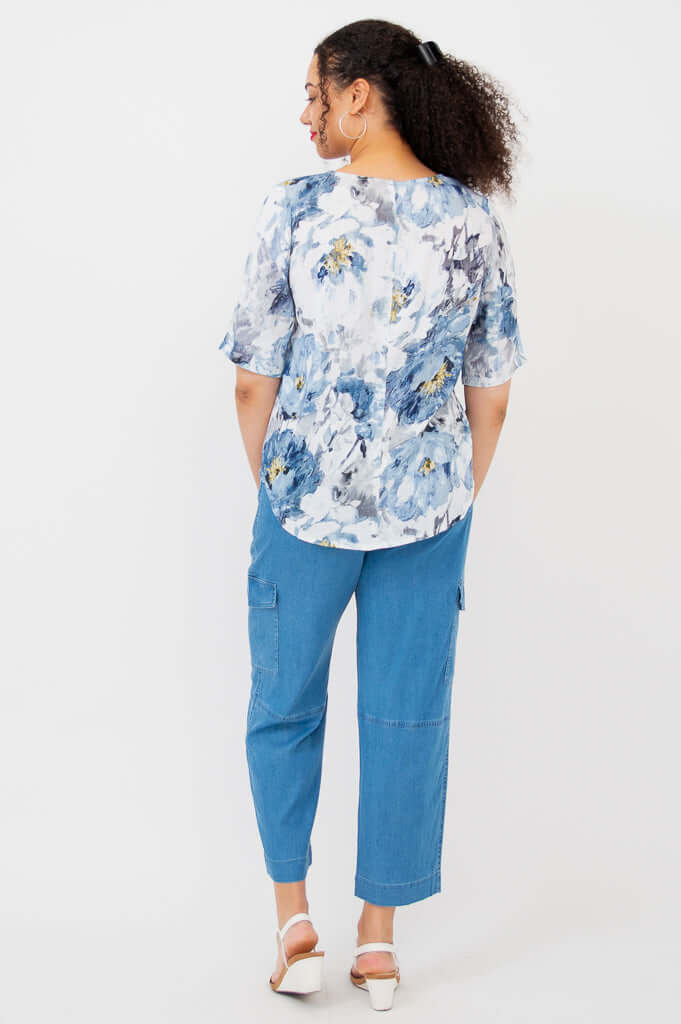Back view of a woman in a blue and white floral blouse and blue pants