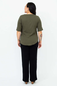 Back view of a woman in an olive green blouse showing shirt tail hem and sleeve length