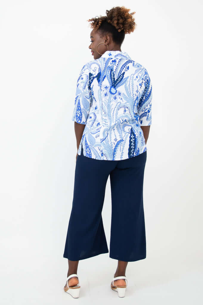 Back view of woman in blue and white paisley print blouse and navy wide-leg pants