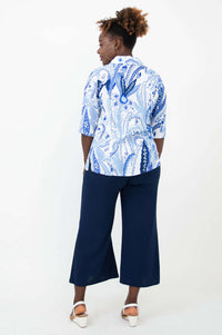 Back view of woman in blue and white paisley print blouse and navy wide-leg pants