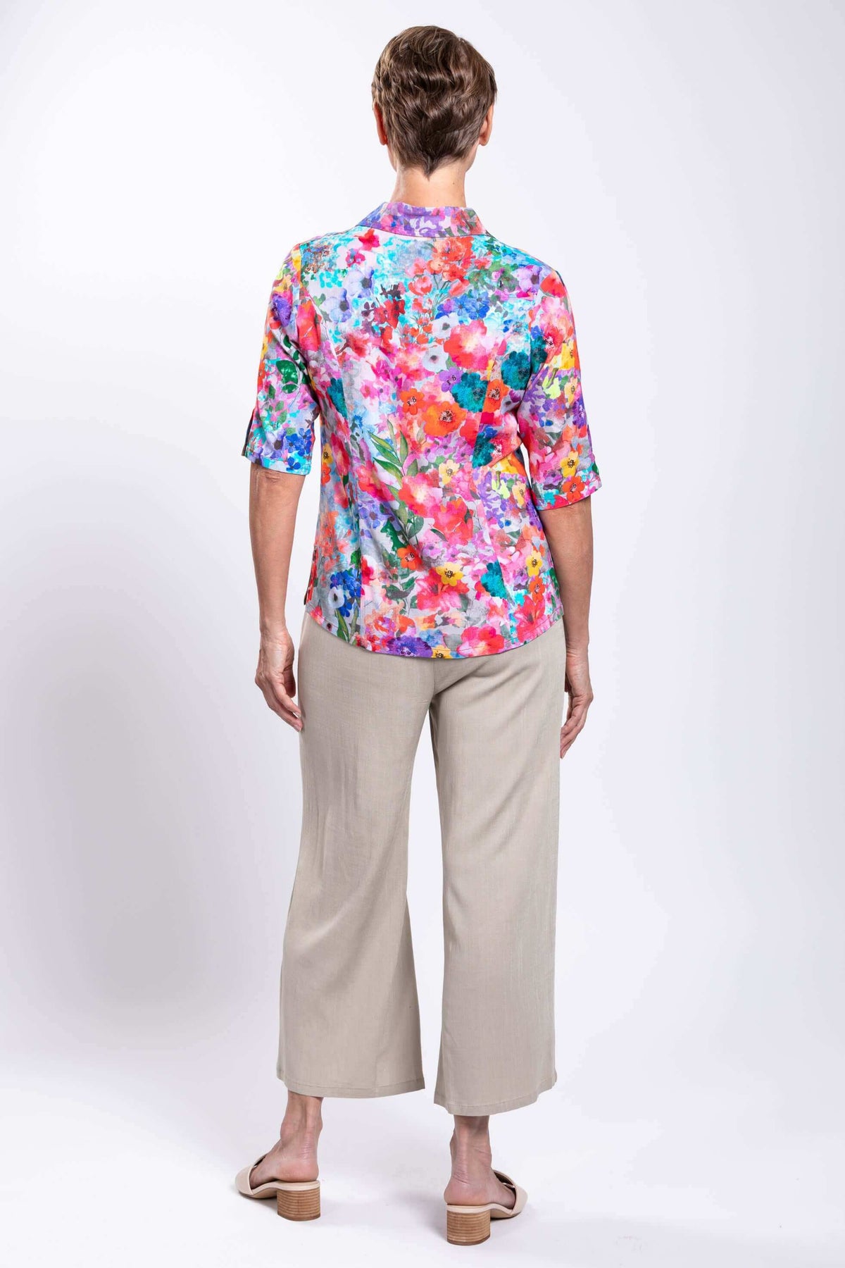 Back view of woman highlighting the floral bamboo linen blouse and neutral pants