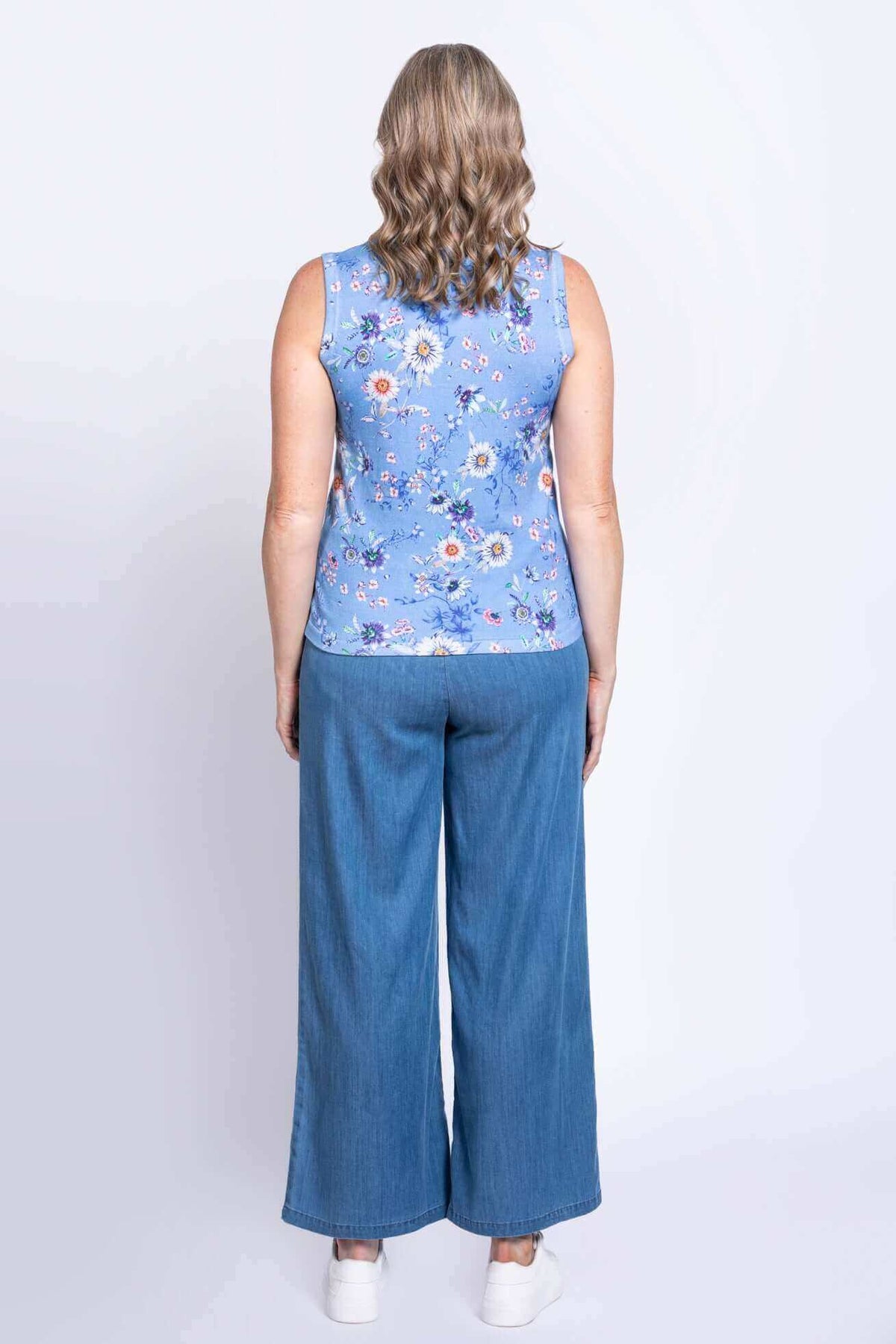 Back view of woman in blue floral tank top and wide-leg jeans