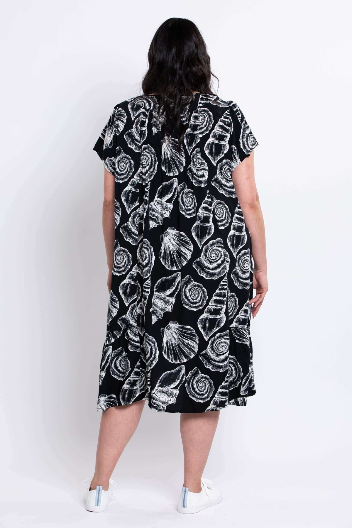 Back view of woman in black shell print dress with ruffled hem