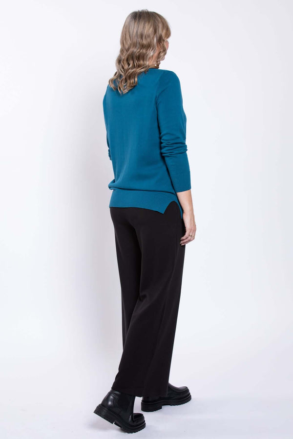 Back view of a woman in wide-leg black pants and teal sweater
