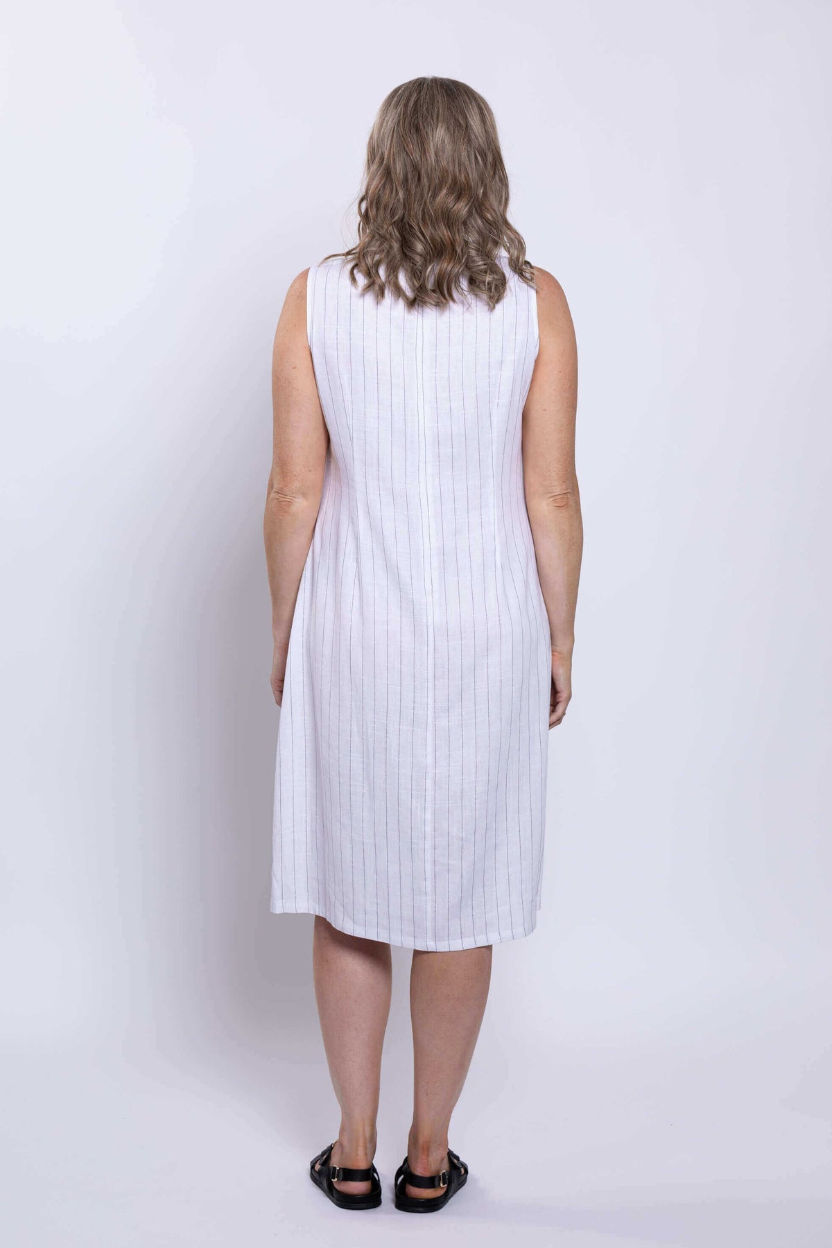 Back view of woman showing the length and fit of a sleeveless white striped dress