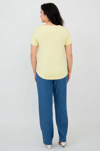 Back view of a woman in a yellow scoop neck tee and blue pants