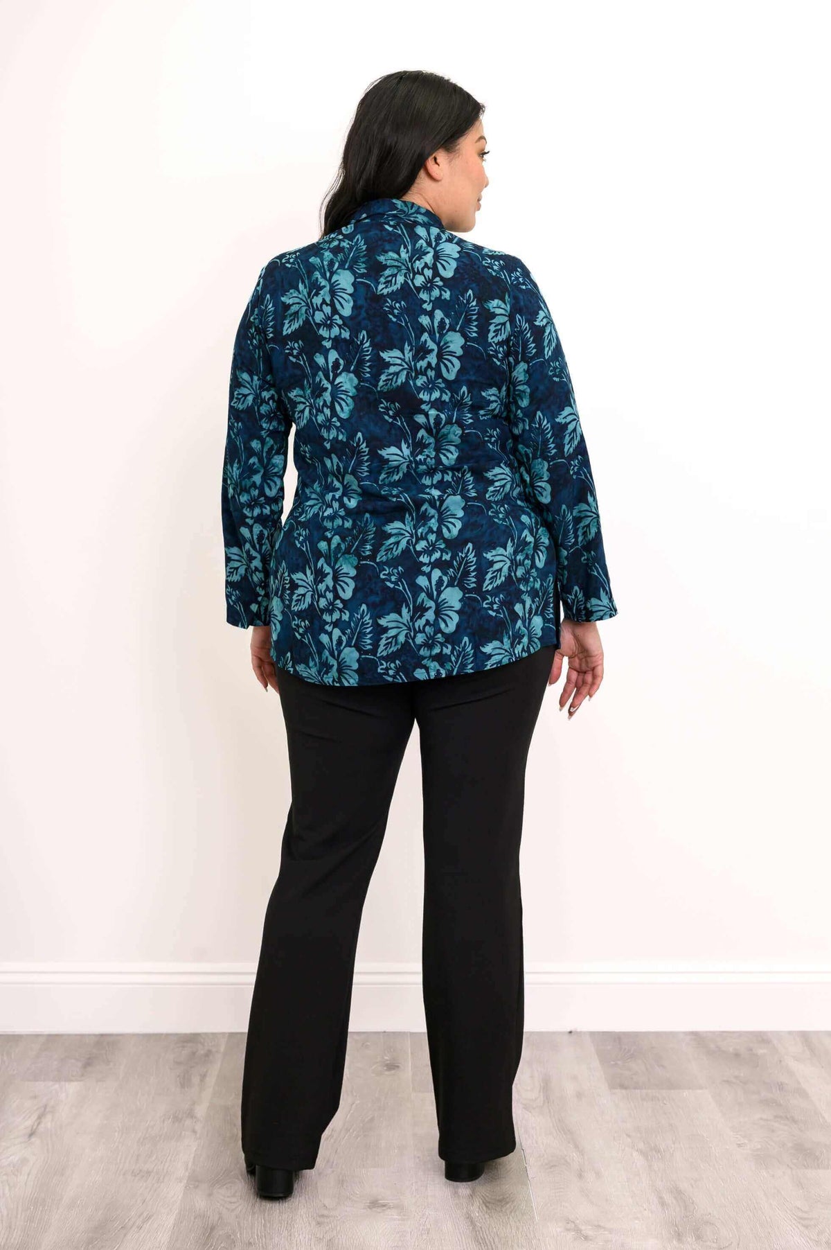 Back view of woman wearing The Cindy blue floral smocked top and black pants