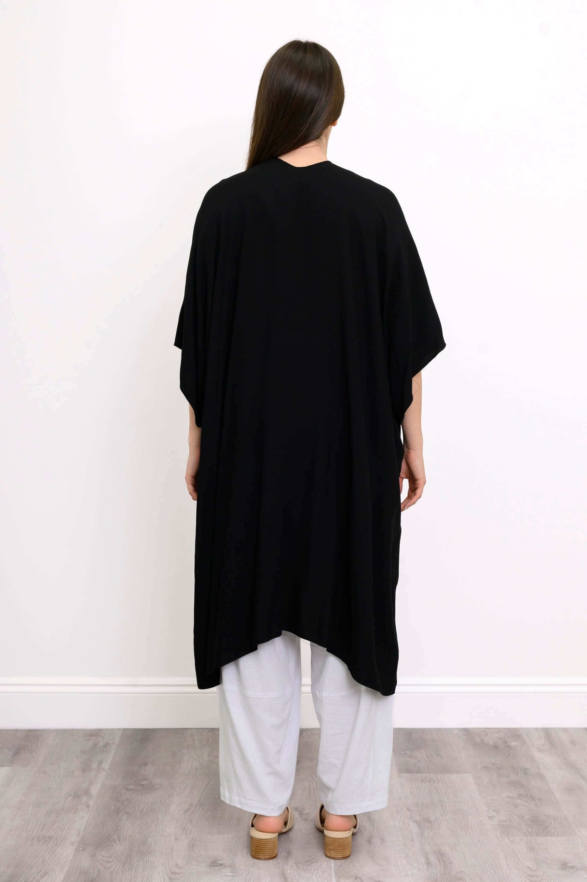 Back view of woman in black Darcy kimono wrap showing draped hemline