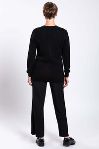 Back view of a woman showing the cable knit pattern of a black cardigan