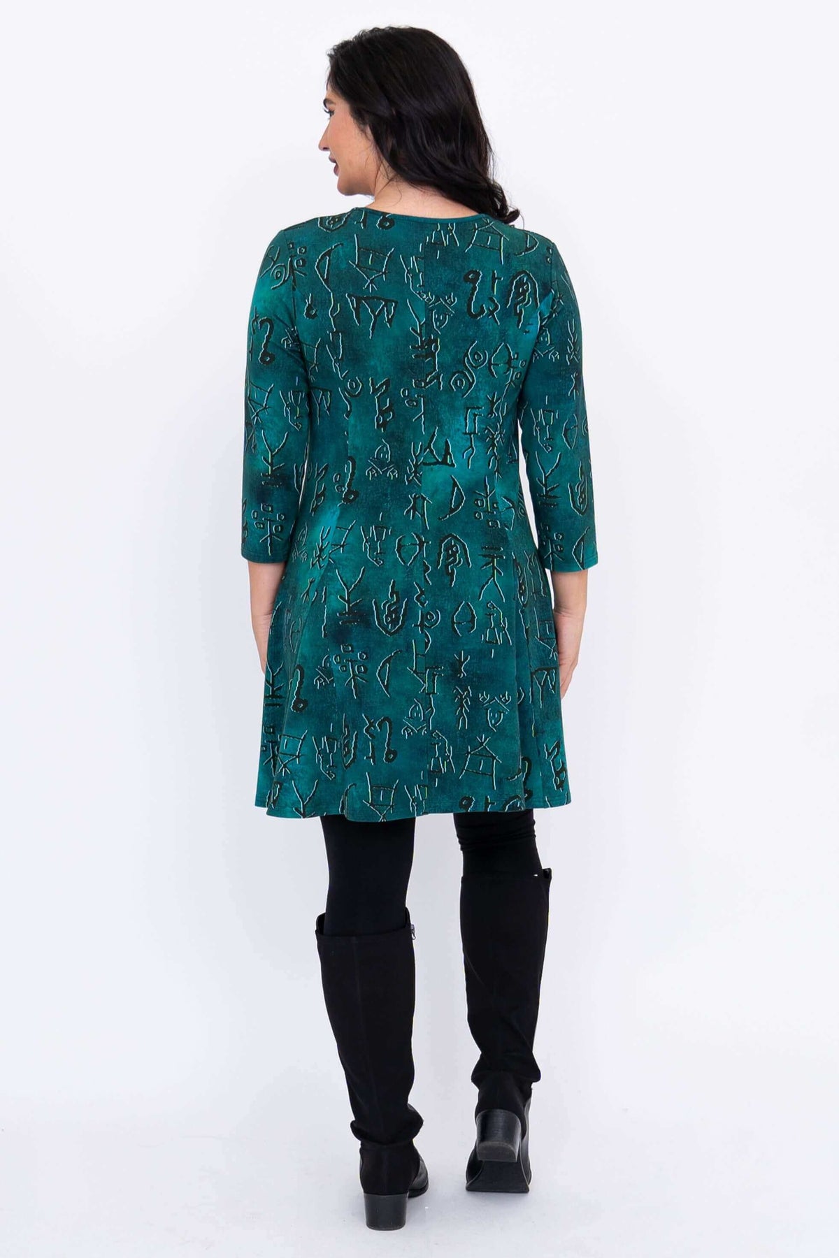 Back view of teal abstract print Wilma Tunic dress, styled with black leggings and boots