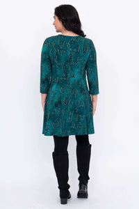 Back view of teal abstract print Wilma Tunic dress, styled with black leggings and boots
