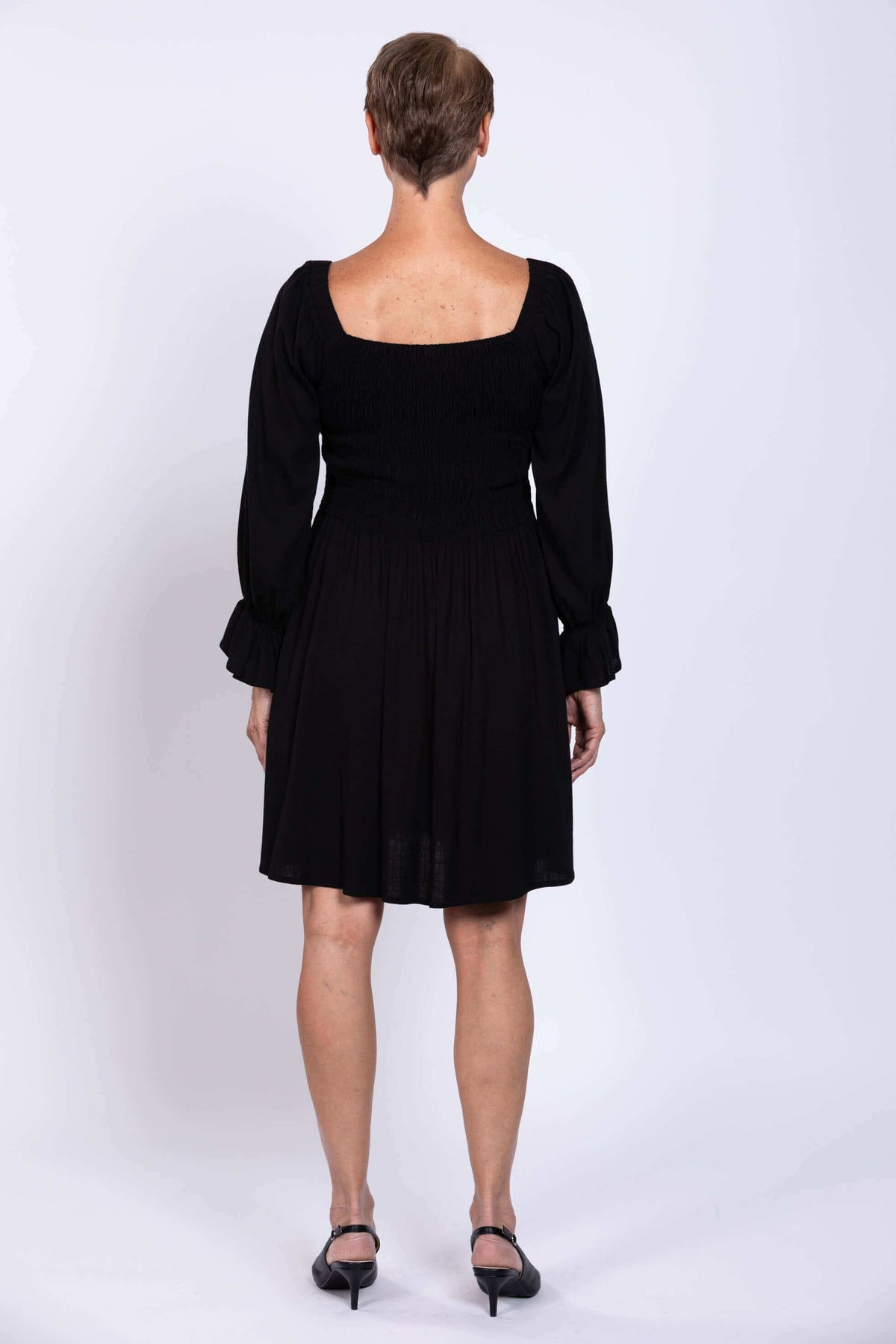 Back view of black dress showing smocked bodice and flared skirt