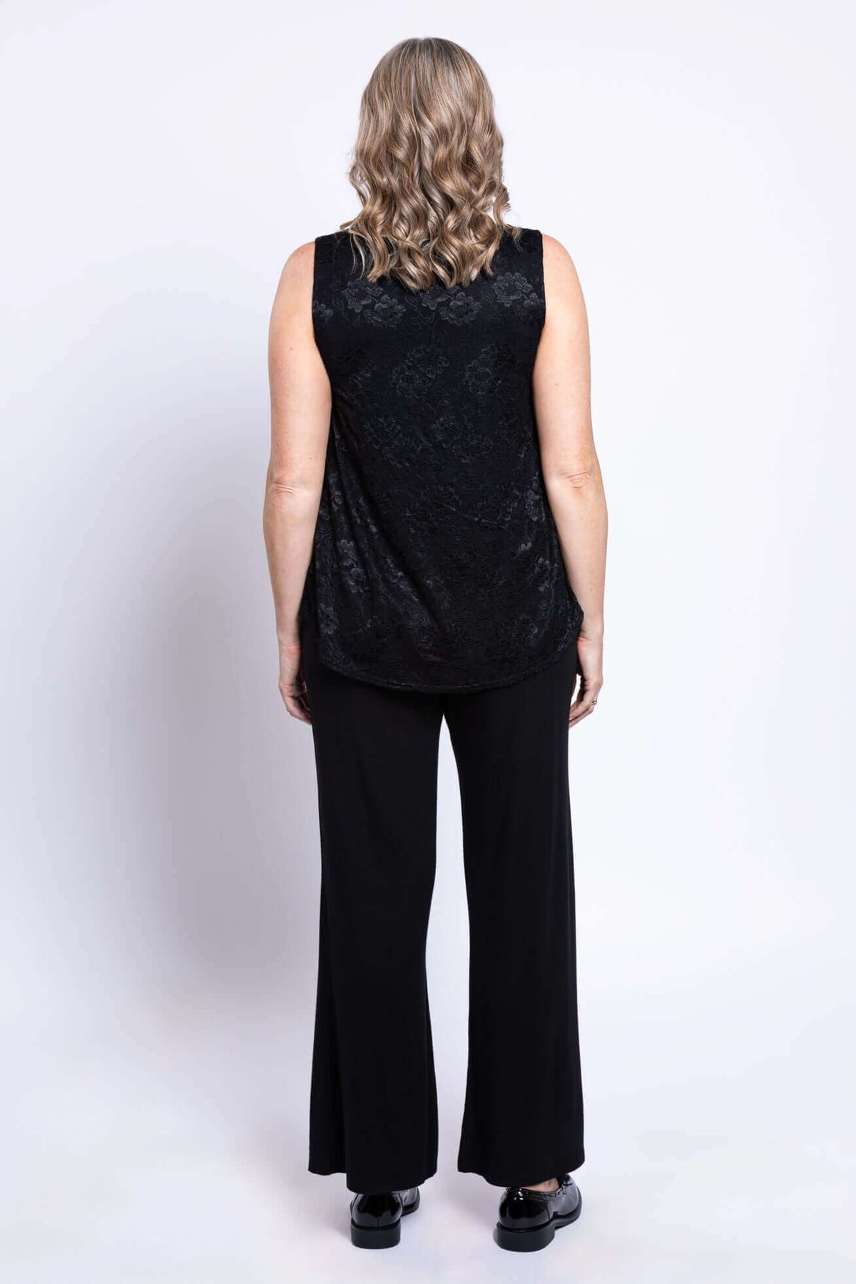 Back view of black lace overlay tank top worn with wide-leg pants