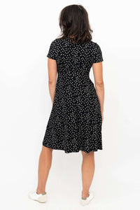 Back view of a woman in a black polka dot A-line dress with short sleeves