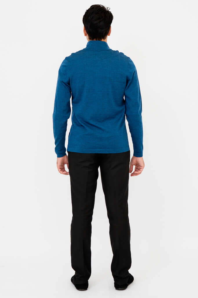 Back view of man wearing blue quarter-zip mock neck sweater and black trousers