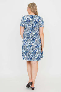 Back view of a woman wearing a blue and white mosaic print dress with short sleeves
