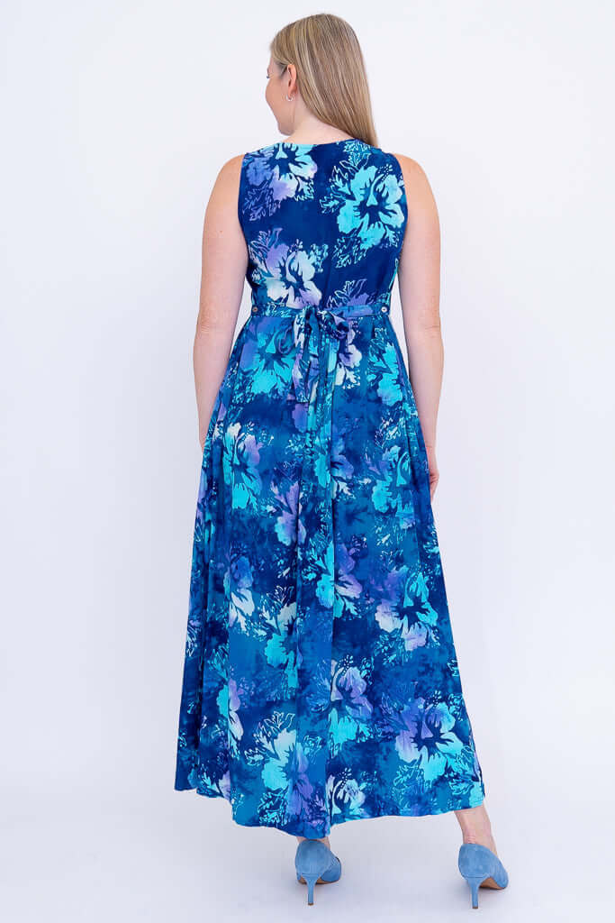 Rear view of a woman wearing a blue floral maxi dress showing the tie detail at the waist