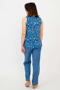 Back view of woman wearing blue floral sleeveless top and blue pants, standing