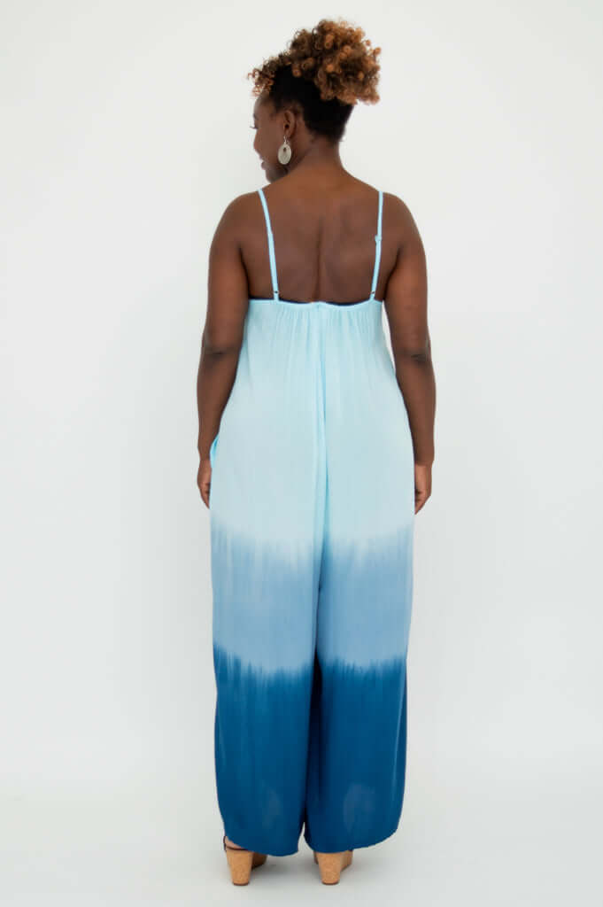 Back view of model wearing a blue ombre jumpsuit with adjustable straps