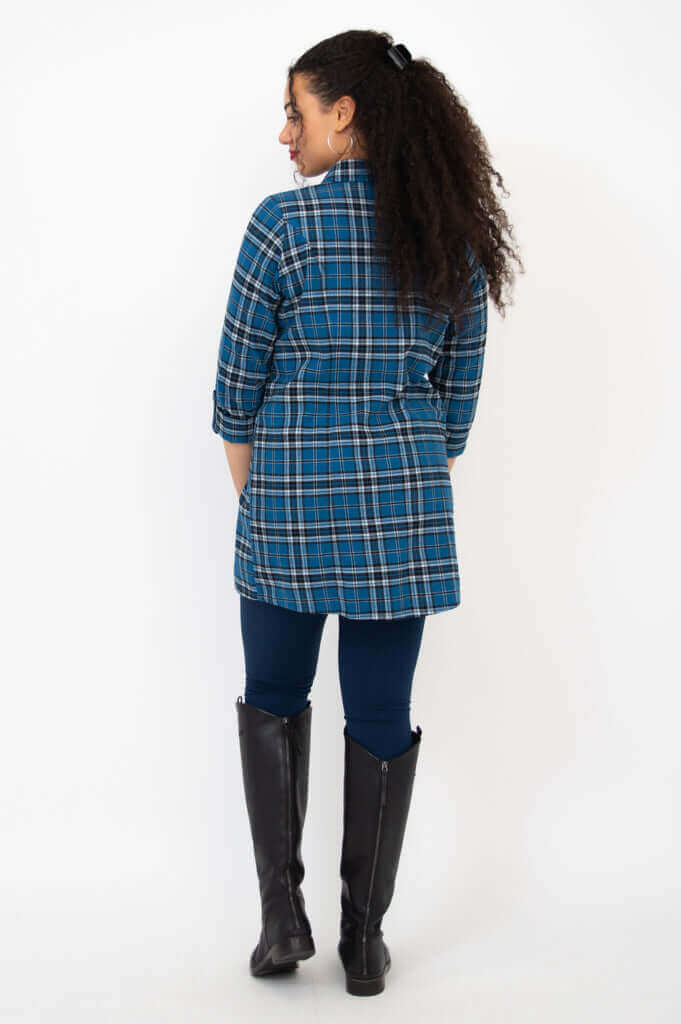 Back view of woman wearing a blue plaid flannel tunic and black boots
