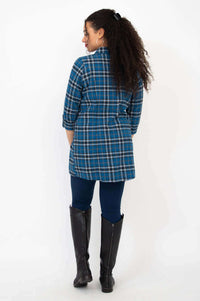 Back view of woman wearing a blue plaid flannel tunic and black boots
