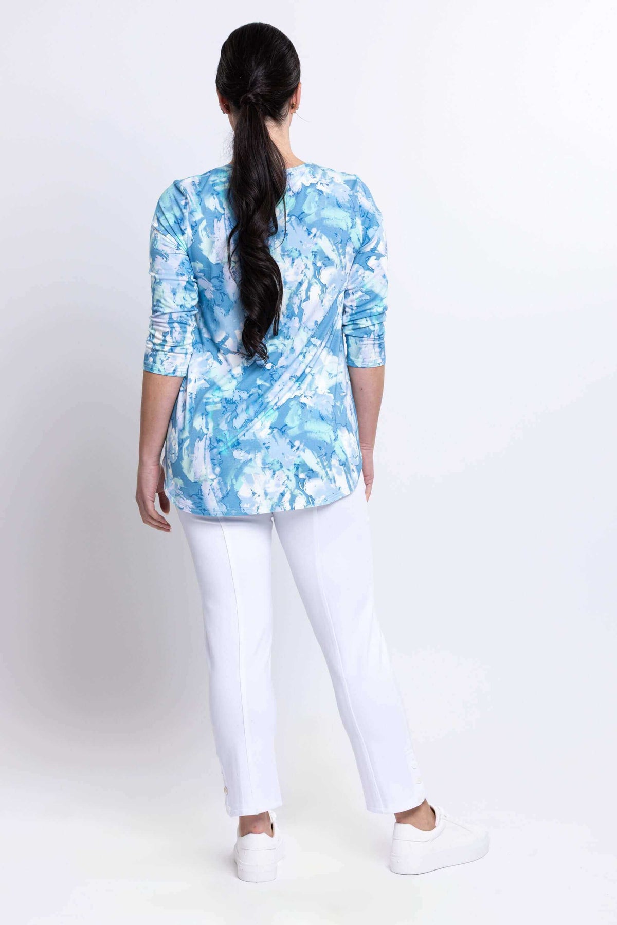 Back view of model wearing blue watercolor bamboo top and white pants
