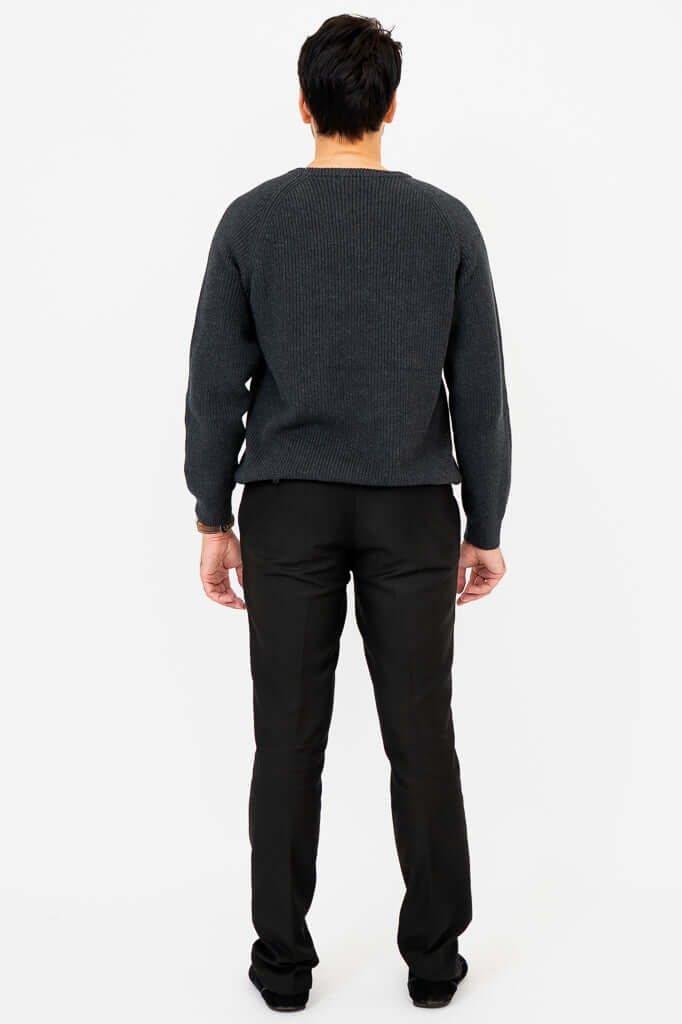 Back view of man wearing a charcoal ribbed crewneck sweater and black pants