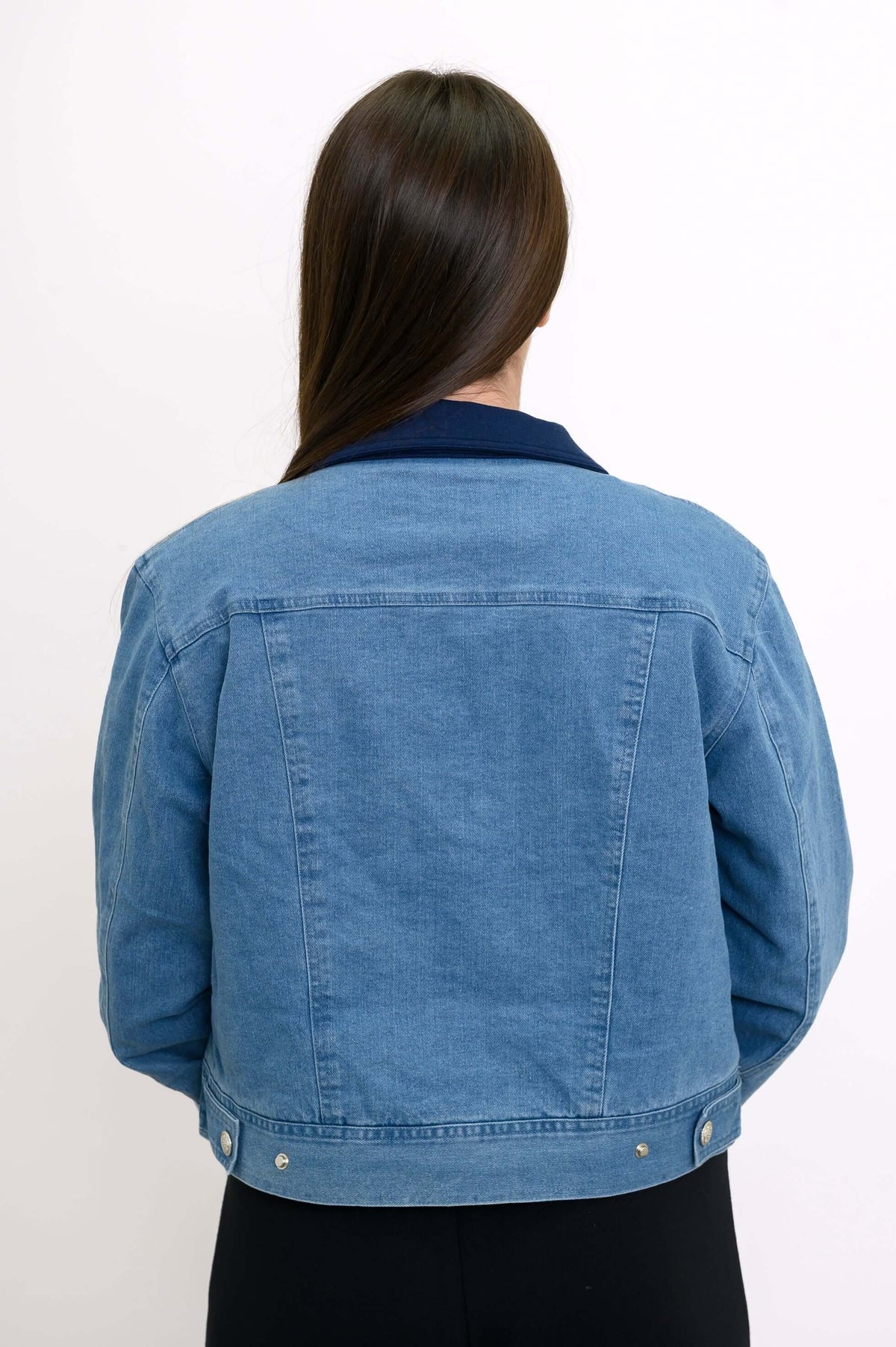 Back view of woman showing the rear detail of a cropped blue jean jacket