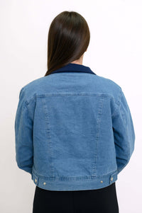 Back view of woman showing the rear detail of a cropped blue jean jacket