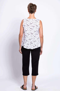 Back view of woman in white floral peplum tank and black pants