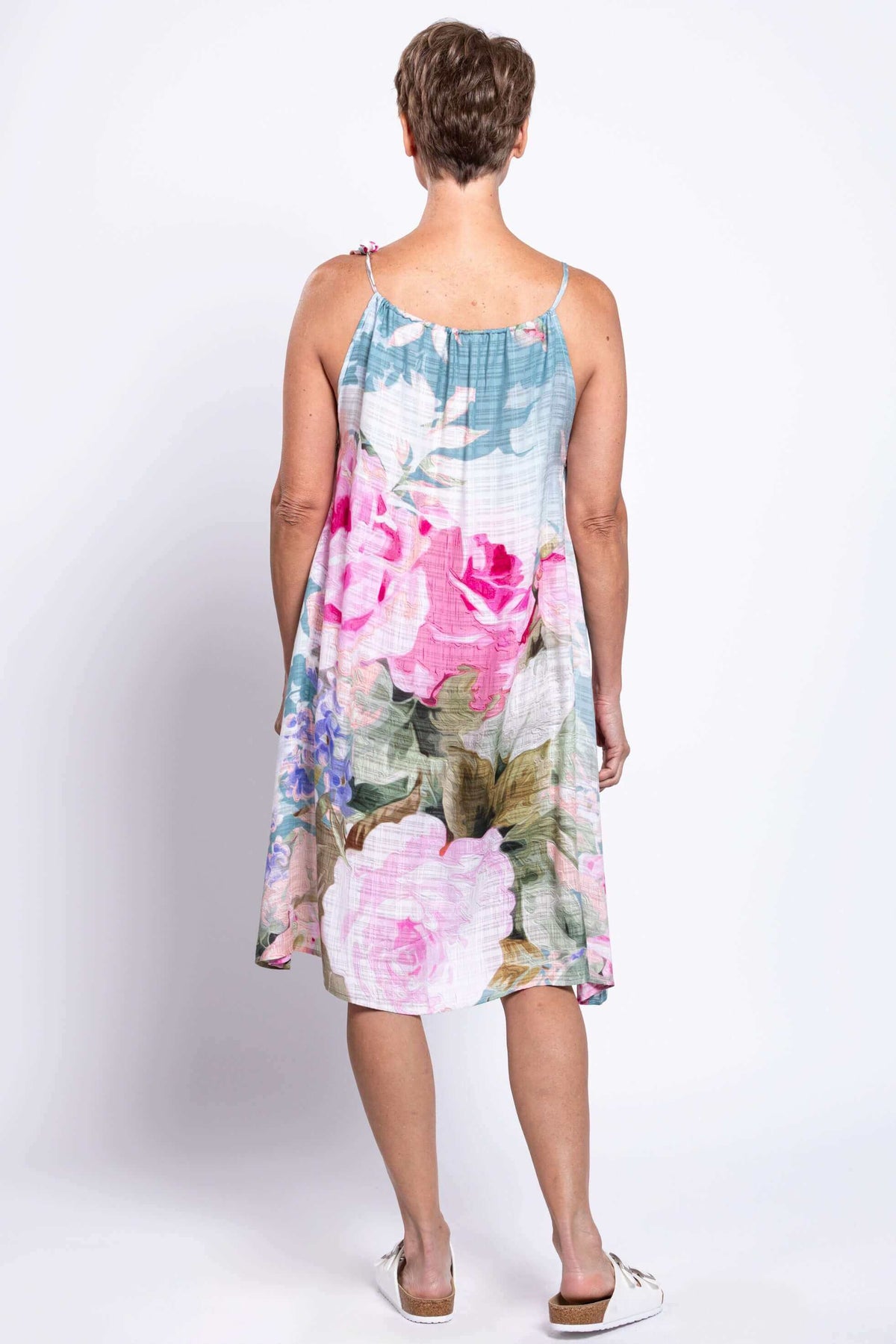 Back view of a woman in a floral knee-length beach cover-up dress with adjustable strap