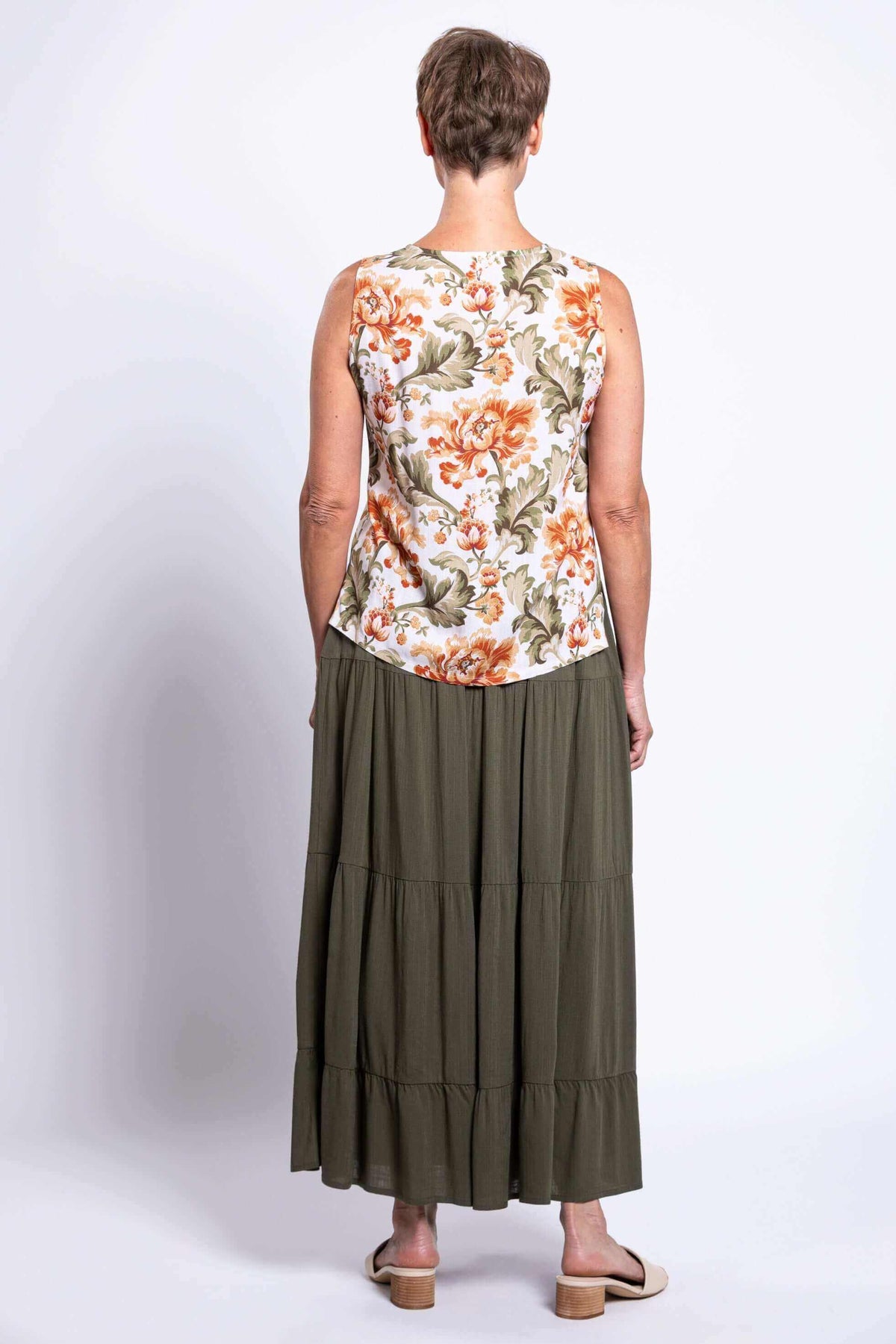 Back view of a woman in the sleeveless floral cropped tank and an olive green maxi skirt