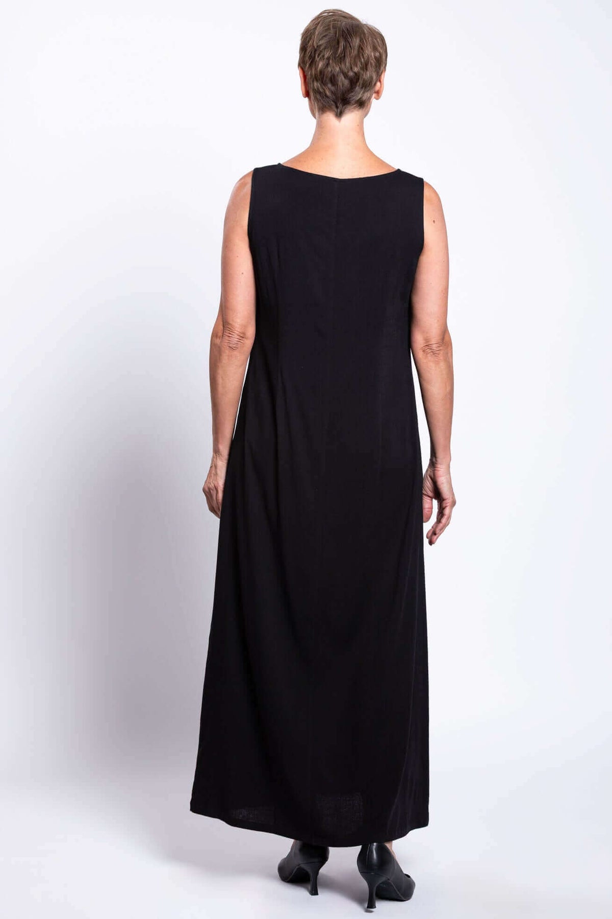 Back view of a woman wearing a full-length black shift dress