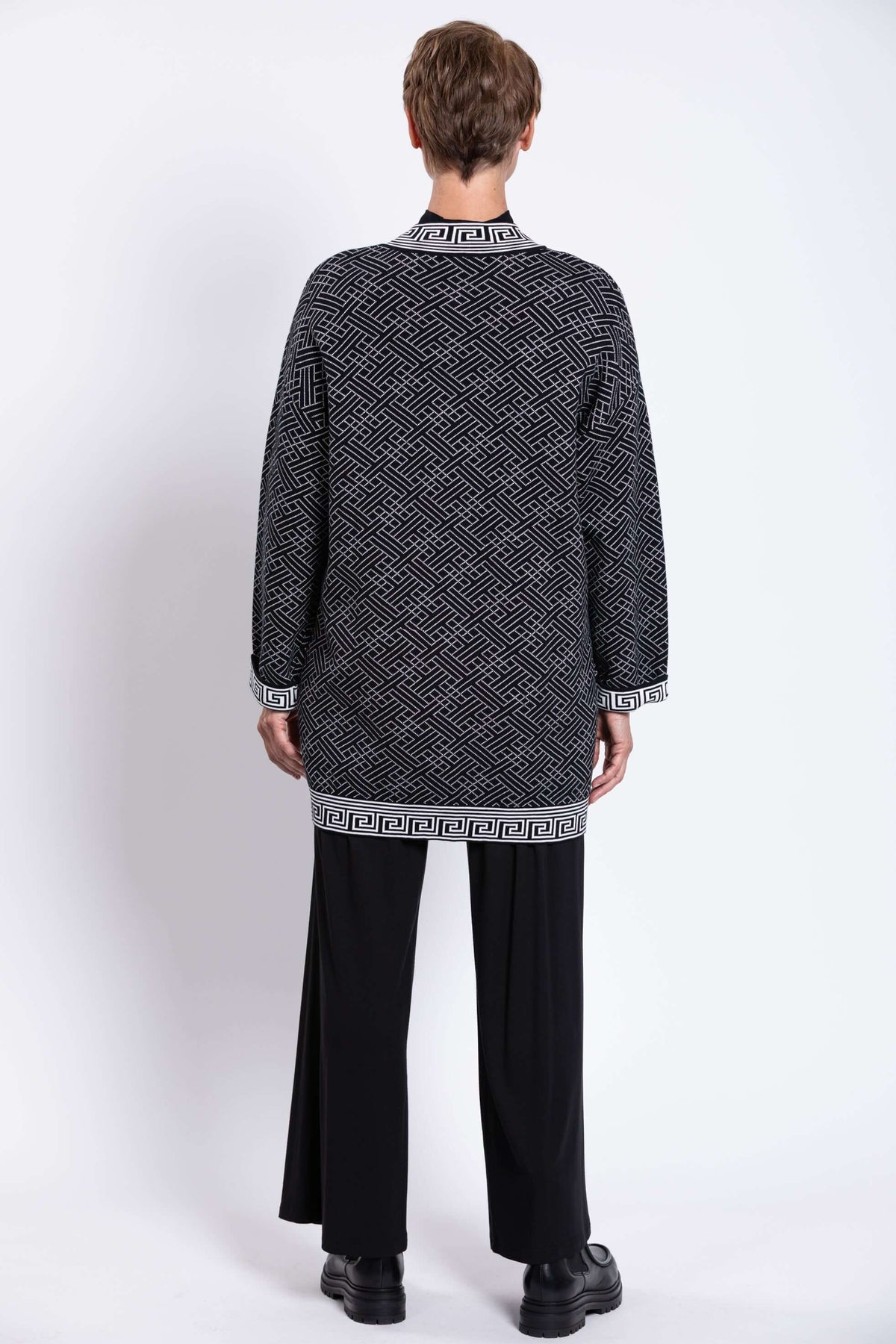 Back view of model in black and white geometric knit long cardigan