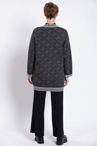 Back view of model in black and white geometric knit long cardigan