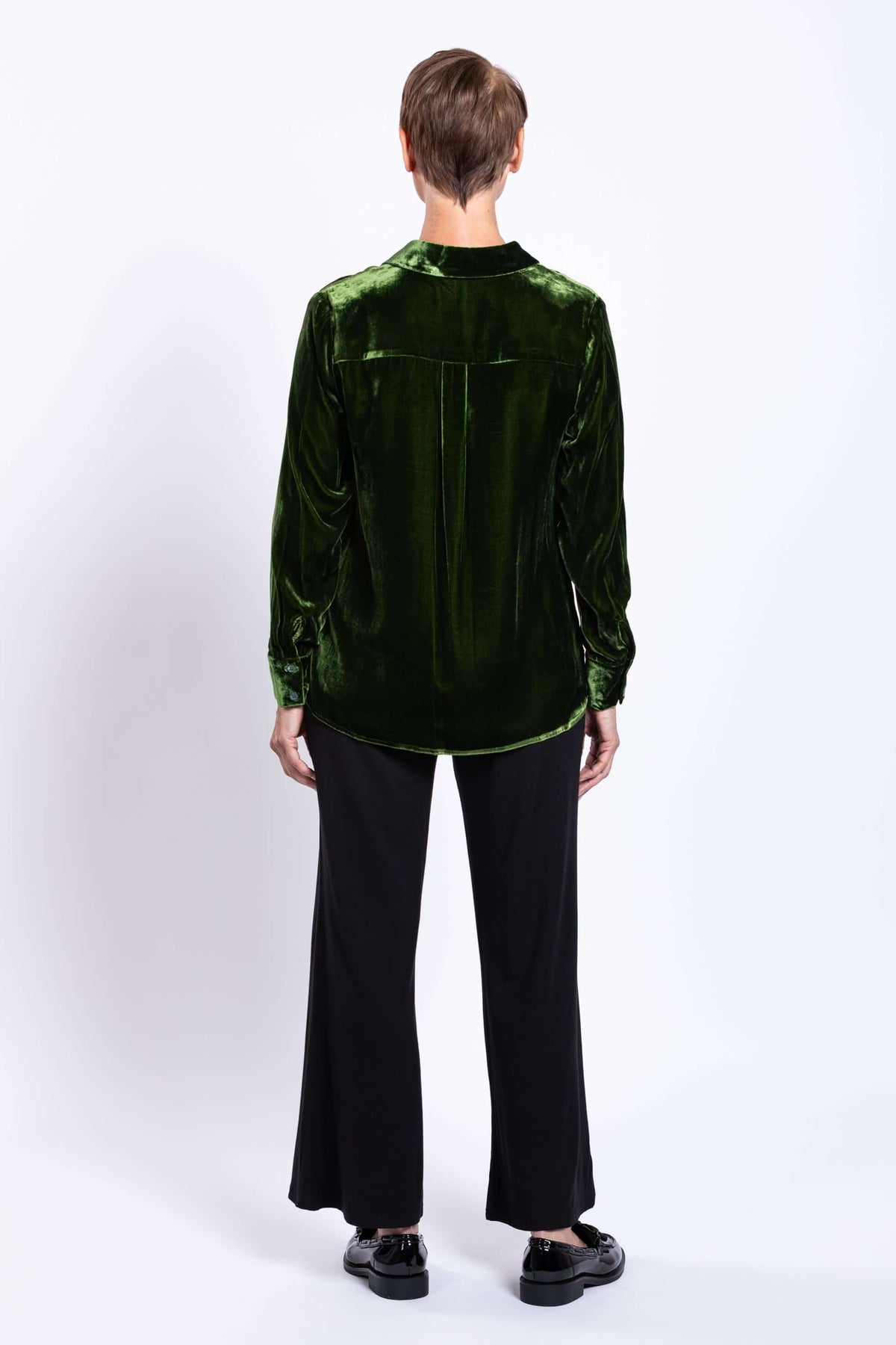 Back view of model wearing green silk velvet blouse showing back pleat detail
