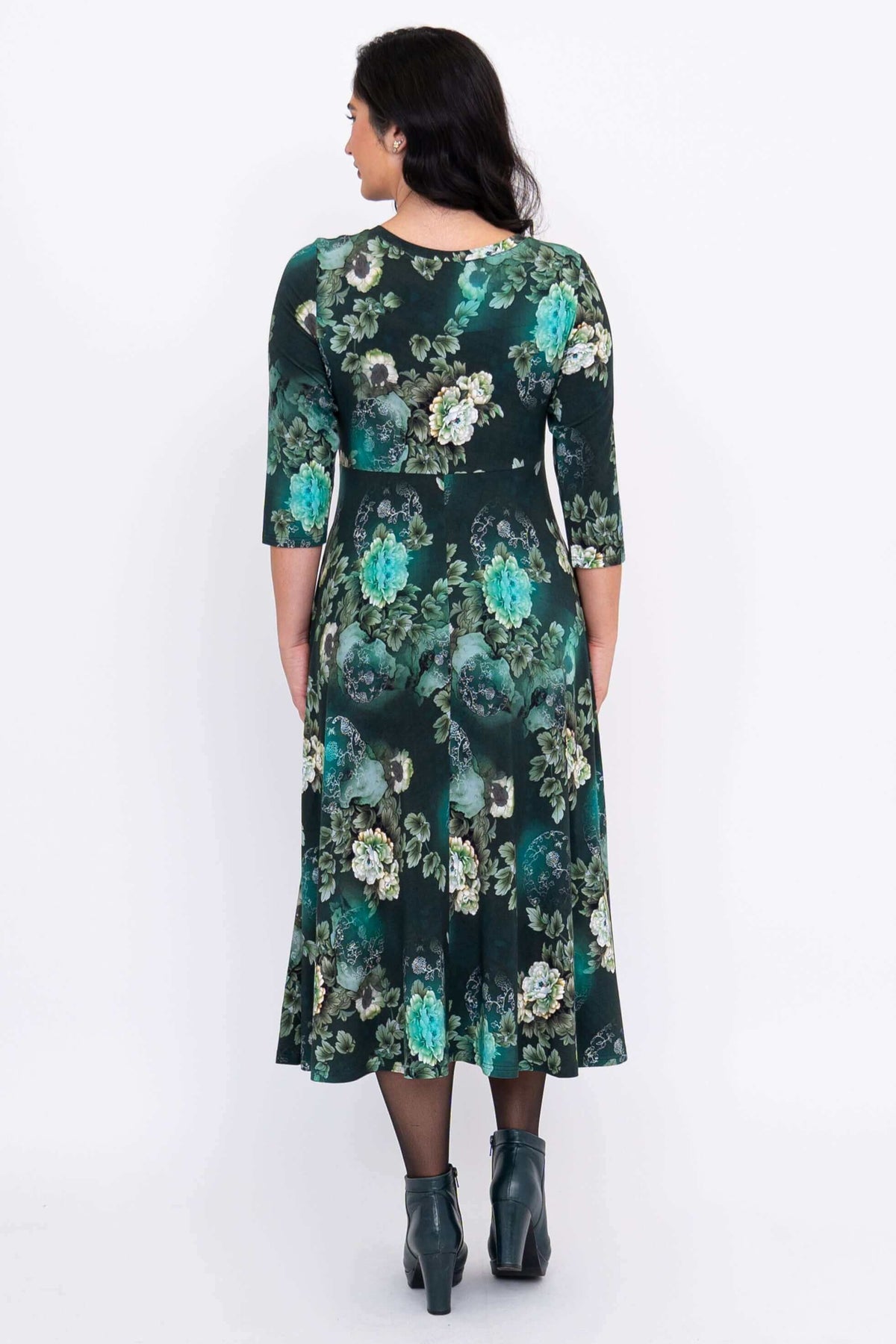 Back view of a woman in a jade green floral midi dress with an A-line skirt