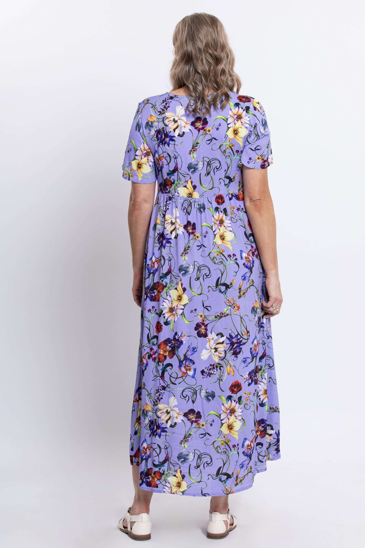 Back view of a woman in a lavender floral maxi dress, showing the empire waist detail
