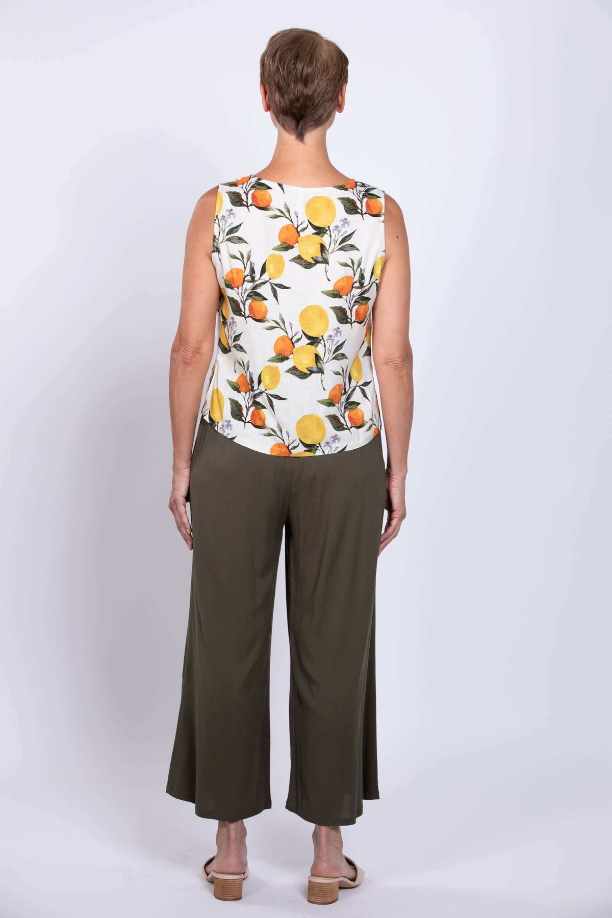 Back view showing fit of white sleeveless tank with lemon and orange print