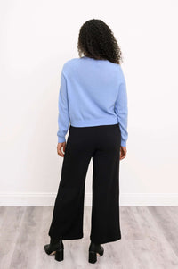Back view of a woman in a light blue cashmere cardigan and black pants