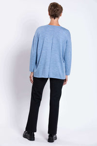 Back view of a woman showing the detail of a light blue knit sweater with black pants