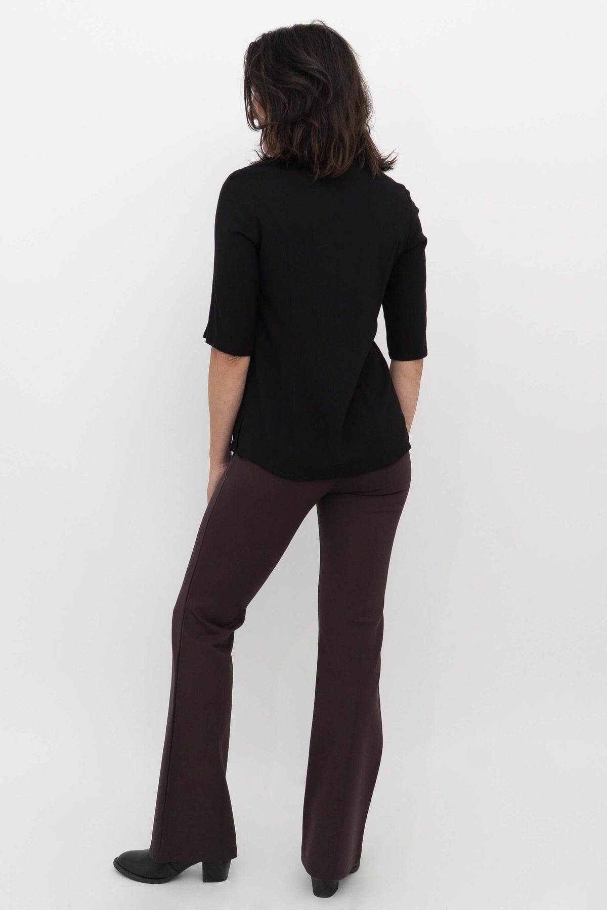 Back view of model wearing Daya Flared Modal Pants in coffee with a black top