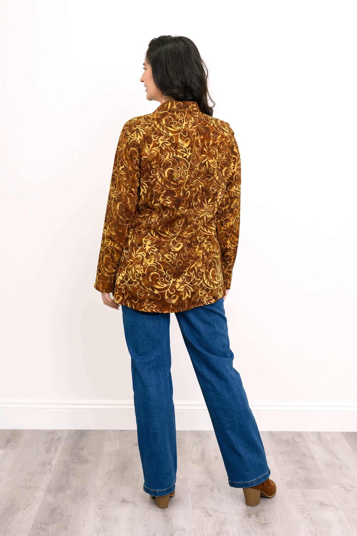 Back view of brown floral smocked shirt on model, paired with blue jeans and brown boots