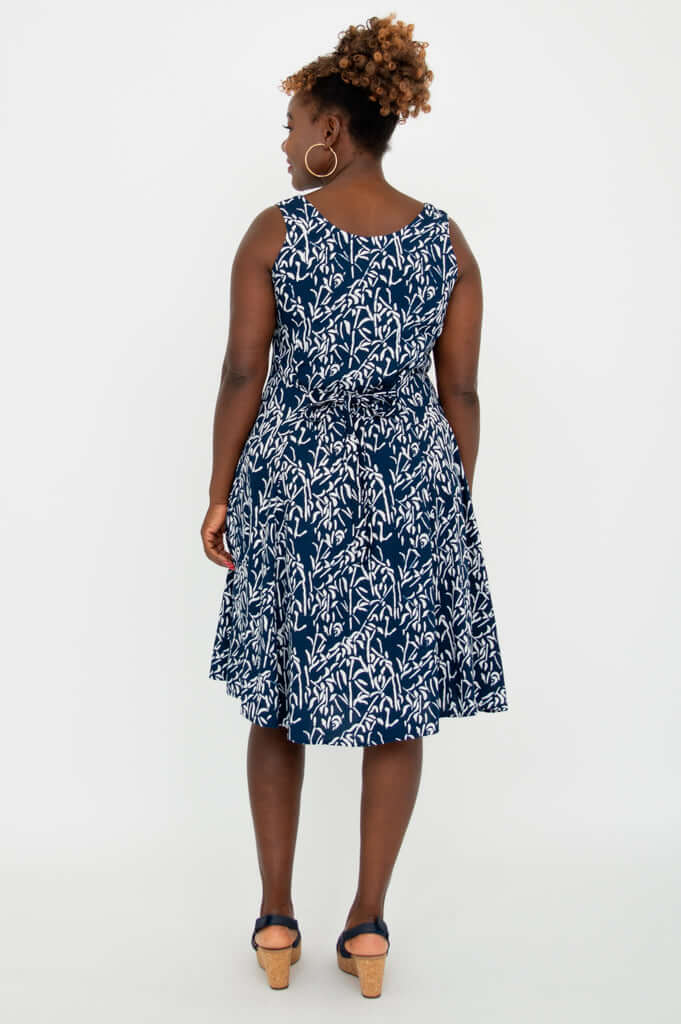 Back view of woman wearing a navy and white sleeveless dress with a tie waist