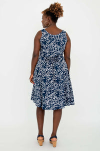 Back view of woman wearing a navy and white sleeveless dress with a tie waist