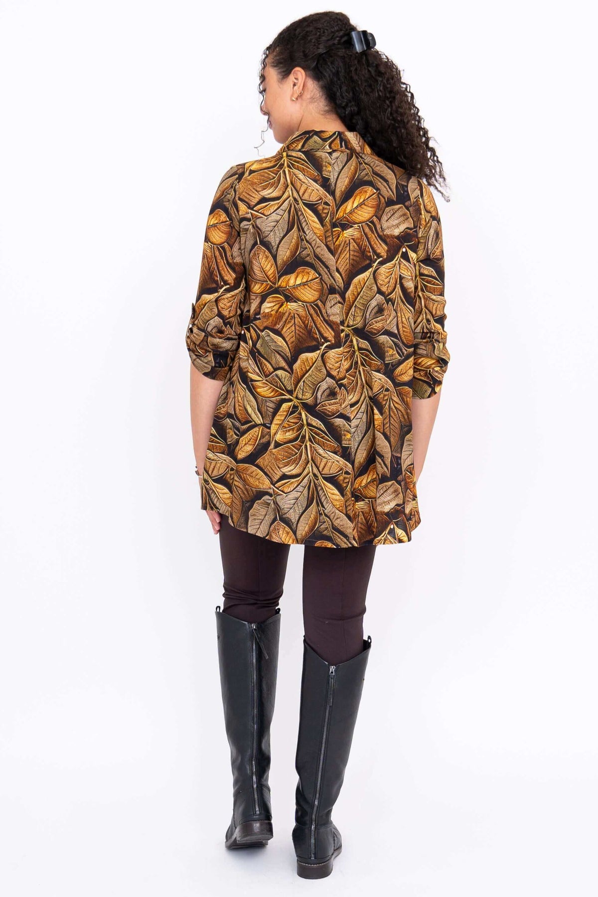 Back view of model wearing oversized brown leaf print tunic with rolled-up sleeves