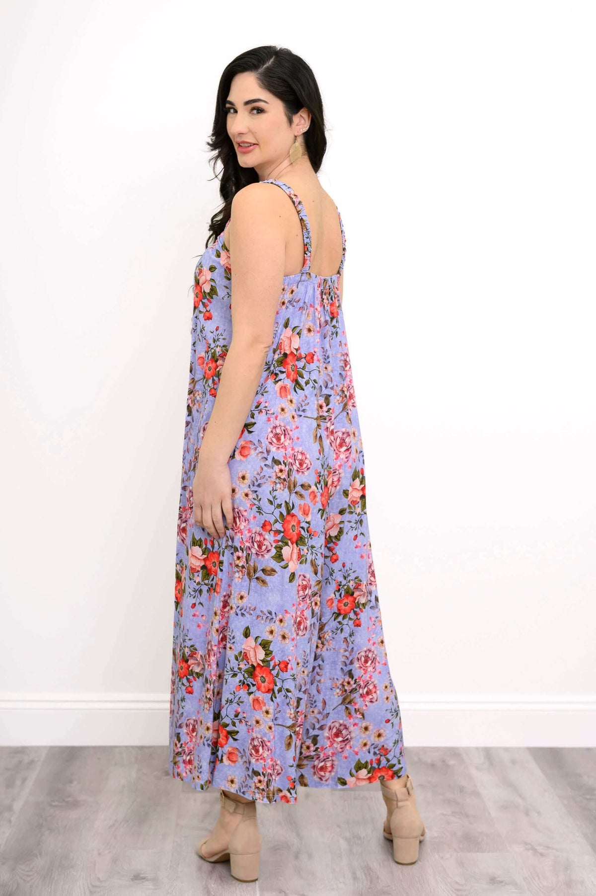 Back view of a woman wearing a purple floral jumpsuit with red and pink flowers