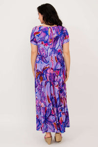 Back view of woman wearing a purple floral maxi dress with keyhole closure and short sleeves