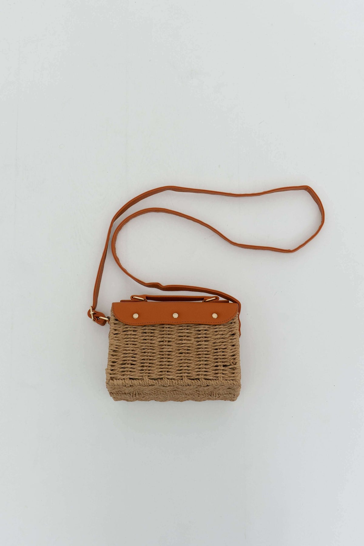 Back view of rattan crossbody bag with brown faux leather and long strap