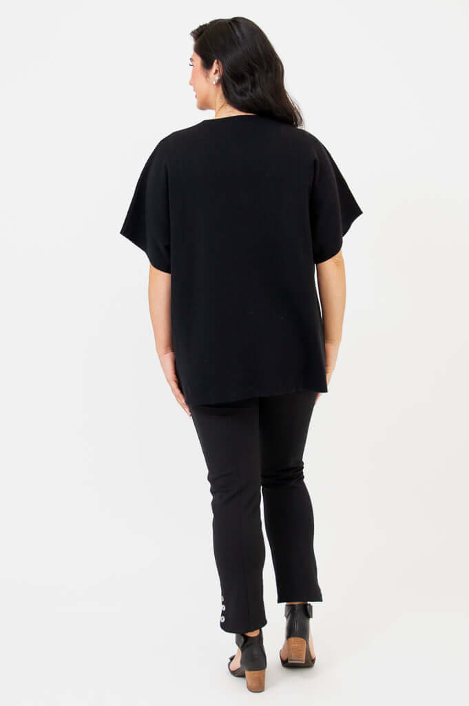 Back view of woman in black short-sleeve cotton cardigan and slim black pants